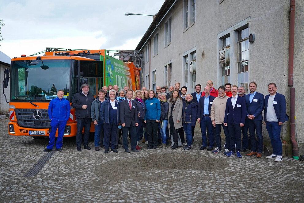 Gruppenfoto der Projektbeteiligten vor einem Abfallsammelfahrzeug.