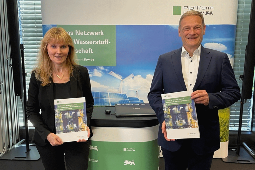 Vor dem Messestand der Plattform H2BW stehen Geschäftführer der e-mobil BW Franz Loogen und Ministerialdirigentin Silke Hepting-Hug des Umweltministeriums und halten jeweils eine Studie in den Händen.