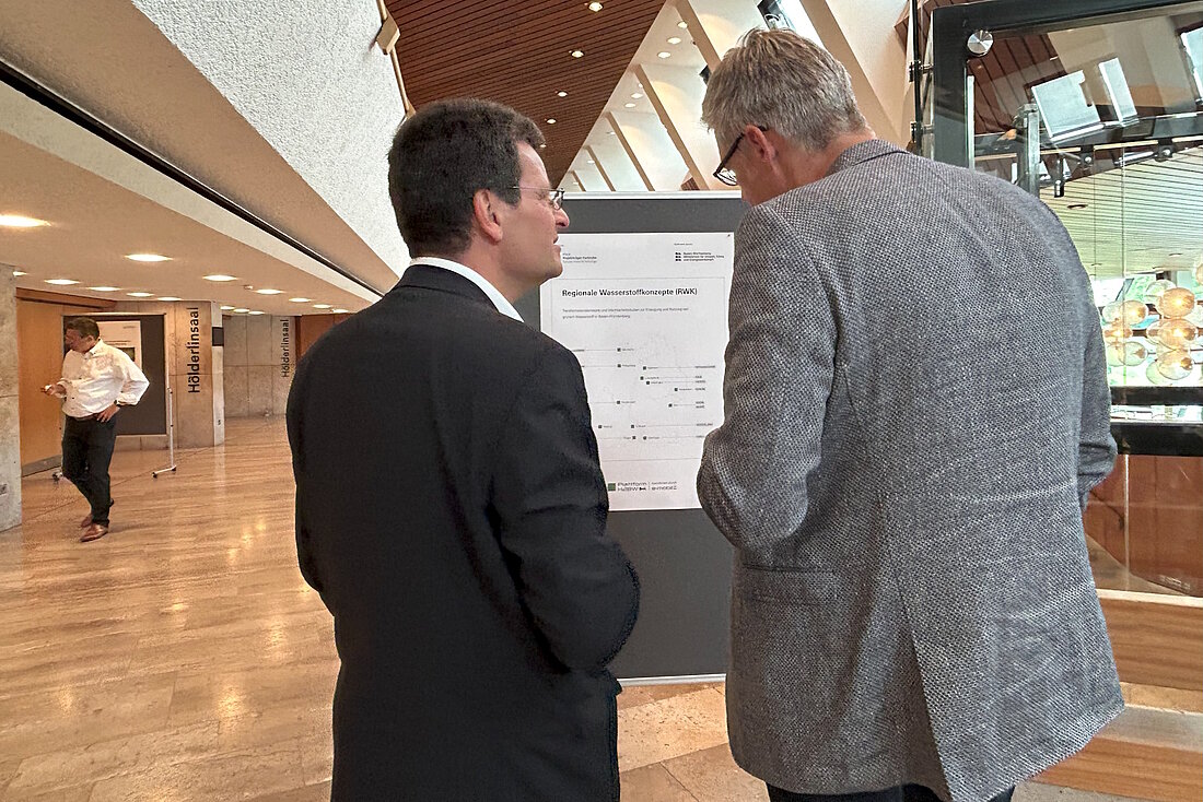 Zwei Personen im Gespräch vor einem Projektpopster
