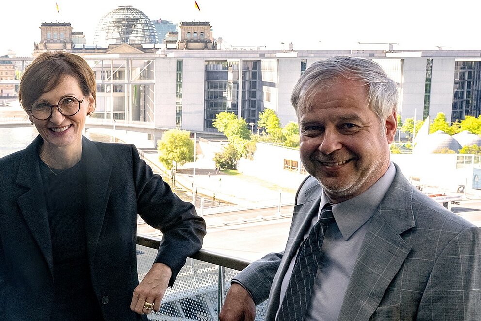 Bundeministerin Bettina Stark-Watzinger posiert gemeinsam mit dem neuen Innovationsbeauftragten Till Mansmann in Berlin mit Blick auf das Reichstagsgebäude.