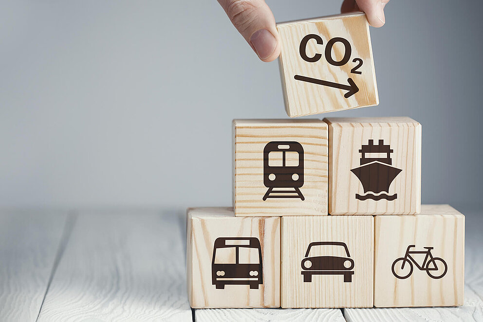 Würfelturm mit Bildern zu Verkehrsmitteln wird um ein Symbol zur CO2-Reduktion ergänzt.