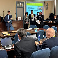 Menschen sitzen in einem Konferenzraum zusammen.