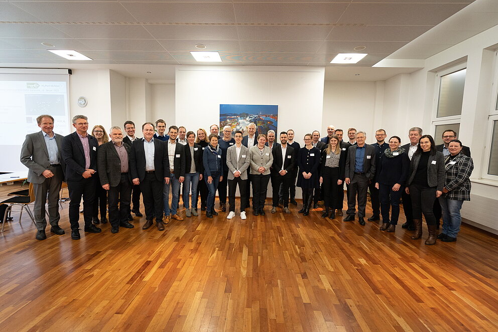 Gruppenfoto von etwa 25 Personen die in einem Halbkreis stehen.