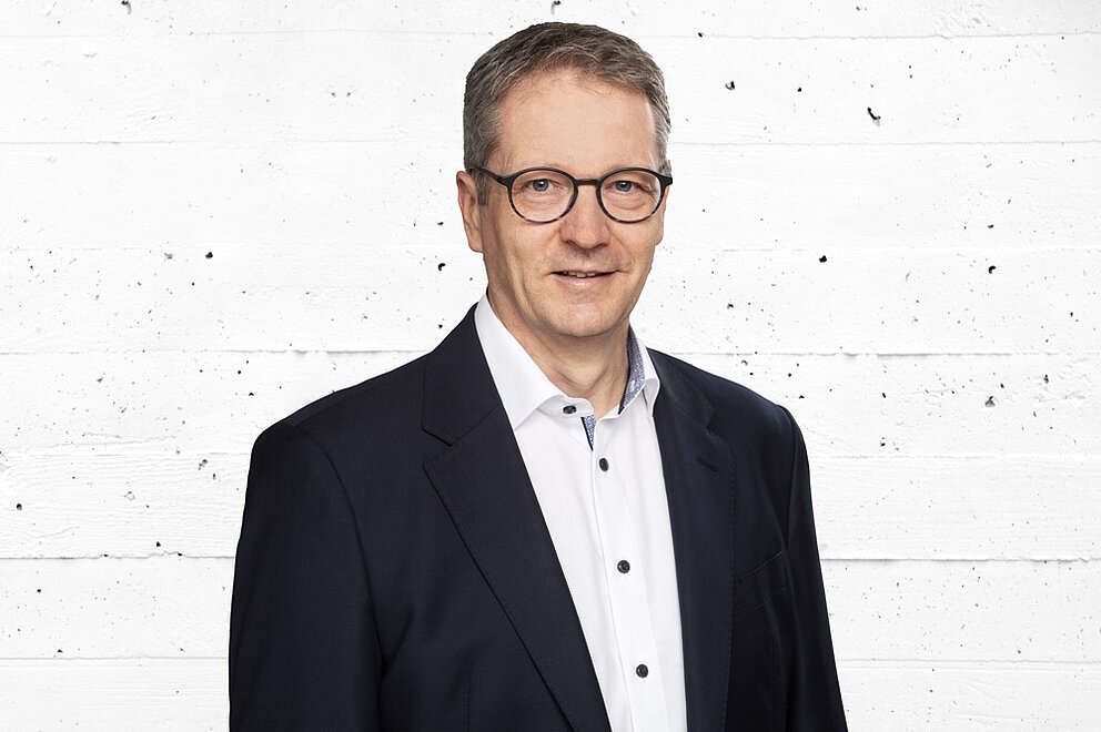 Porträt von Bernd Schneider vor einer grauen Betonwand