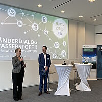 Eine Referentin und ein Referent stehen vor einer Präsentation