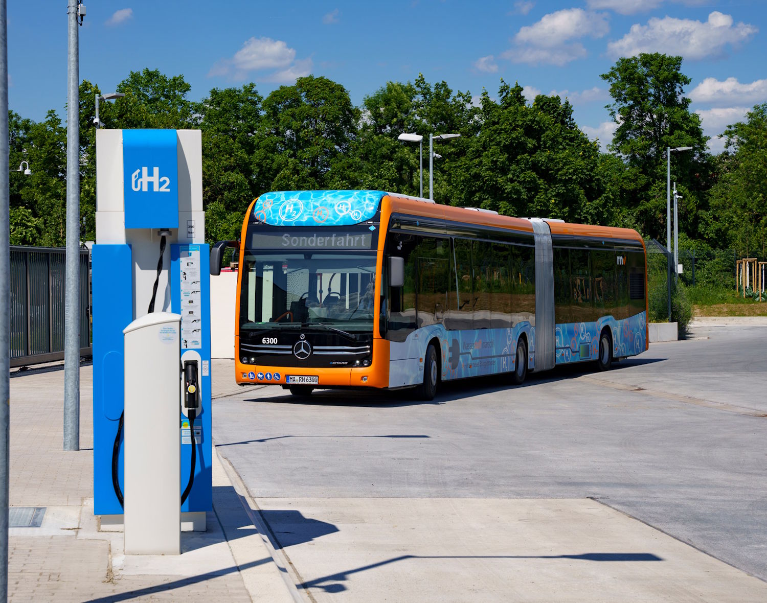 Ein Gelenkbus mit Brennstoffzellenantrieb fährt an eine Wasserstofftankstelle.