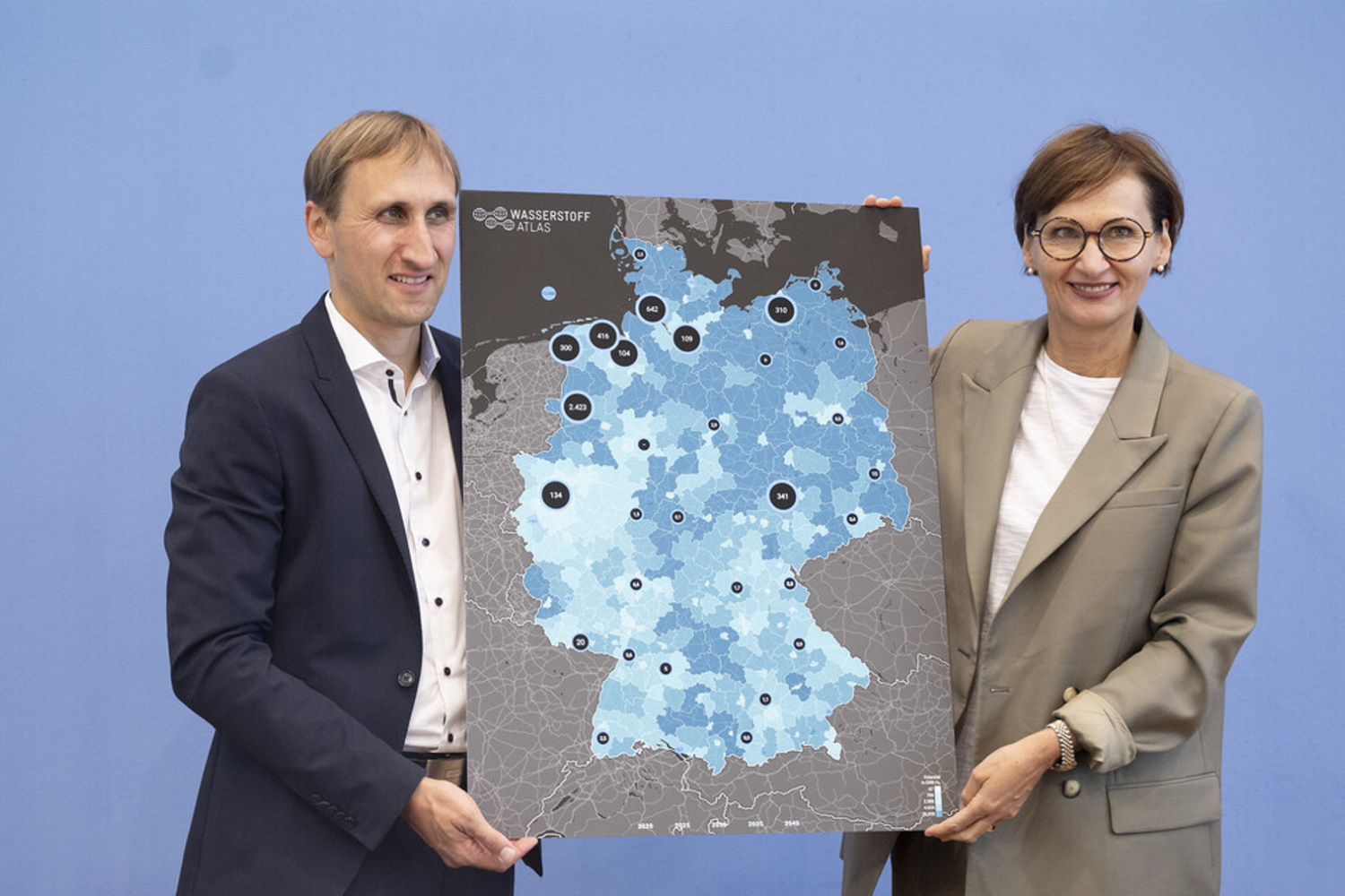 Bundeministerin Bettina Stark-Watzinger und Professor Michael Sterner halten ein Plakat mit einer Deutschlandkarte in die Kamera.
