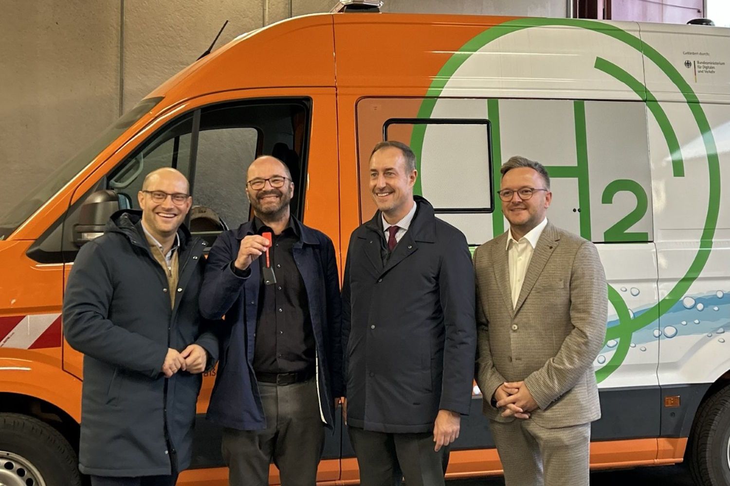 Vor dem neuen Brennstoffzellen-Fahrzeug stehen Landräte und Vertreter des Bundes