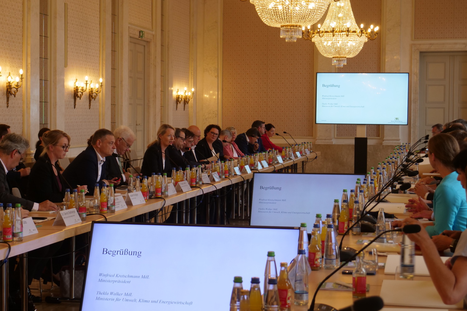 Teilnehmer sitzen im Saal im neuen Schloss in Stuttgart am Konferenztisch